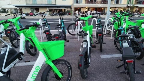 Camera pan right of green rental electric bikes parking in Nice 스톡 동영상 336923145