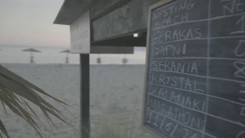 Camera pan from a sign recording turtle nests to the beachfront at sunset Stock Footage 238780054