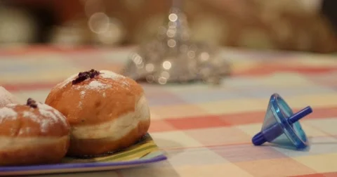 Camera pan from a static Dreidel to a plate of Hanukkah Doughnuts Video stock 56984567