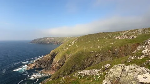 Camera panning 360 degrees and following girl walking by the cliff and sea Stock Footage 163605587