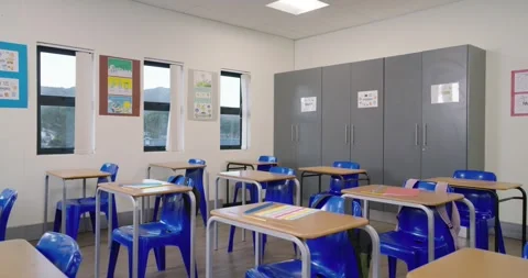 Camera is panning across classroom to reveal desks, chairs, backpacks, posters, Stock Footage 340631323