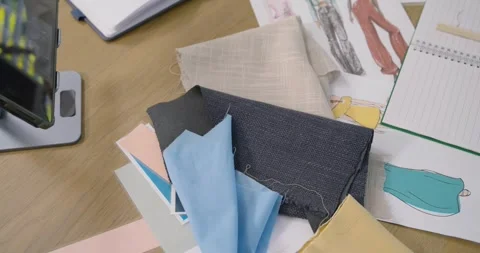 Camera is panning up and left, showing fabric swatches, fashion sketches, Stock Footage 340654345