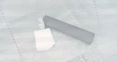 Camera panning and rotating, showing mat, towel, bottle on tiled floor, implying Video stock 332401808