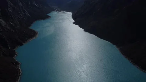 Camera panning down along blue water of Laguna Peron from Snow capped mounta Stock Footage 252374833