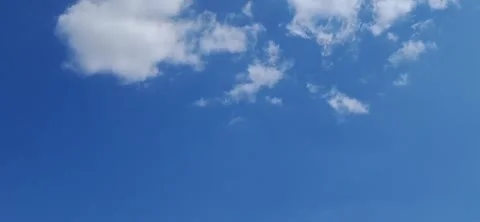Camera panning down from bright blue sky with fluffy white clouds Video stock 342038019