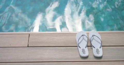 Camera is panning down to reveal striped flip-flops sitting on wood deck beside Stock Footage 342802082