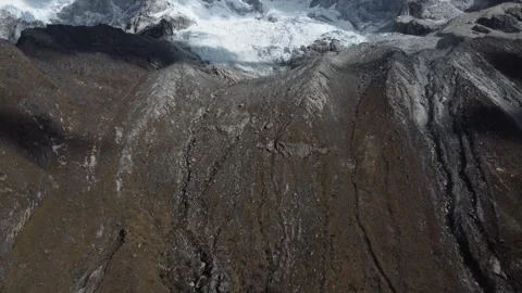 Camera panning down from snowcapped mountains to a waterfall of the melting  Stock Footage 252375875