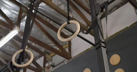 Camera is panning down while wooden gymnastic rings are swinging and rotating to Stock Footage 342031878