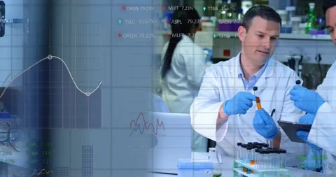 Camera panning, lab lead holding orange test tube, team checking sample with Stock Footage 330577931