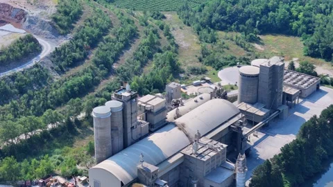 Camera panning over cement factory complex surrounded by forest Stock Footage 285085068