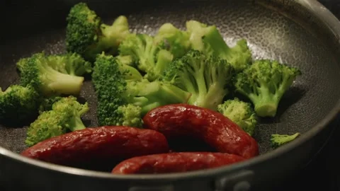 Camera panning over frying pan with sizzling sausages and broccoli Stock Footage 346903286