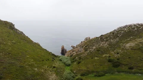 Camera panning over green cliffs to reveal ocean vista Stock Footage 300620926