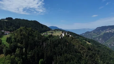 Camera panning over green hills revealing mountain village Video stock 284979683