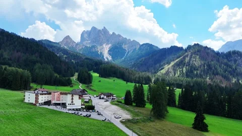 Camera panning over green valley with buildings and mountains Video stock 285081259