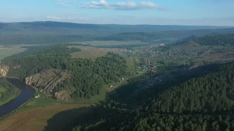 Camera panning over small village by river and forest Vídeo Stock 311869980