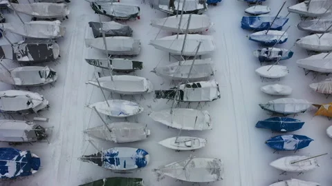Camera panning over snow covered boats in storage yard, aerial view Stock Footage 289005034