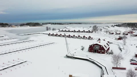 Camera panning over snow covered village with frozen harbor, aerial view Stock Footage 289006721