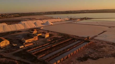 Camera panning over torrevieja pink lake salt mine at sunset Stock Footage 296804687