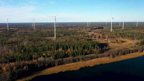 Camera panning over wind farm near lake and forest, aerial view Stock Footage 289013242