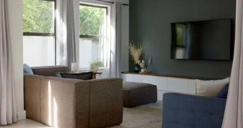 Camera is panning to reveal green wall and TV as sunlight is moving across brown Stock Footage 335625540