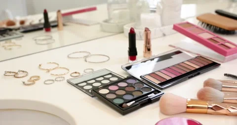 Camera is panning right, revealing palettes, red lipstick and brushes on vanity, Stock Footage 344104891