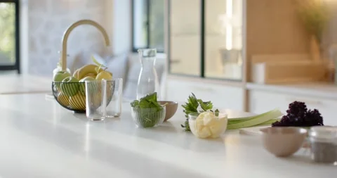 Camera is panning right showing fruit bowl, carafe, leafy greens and blender on Stock Footage 345607446