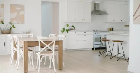 Camera is panning right, showing wood dining table and four white chairs, Stock Footage 345508859