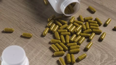 Camera panning shot of pills spilled from white bottle on wooden table Vídeos de archivo 342239985