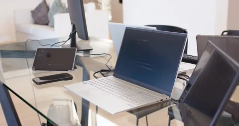 Camera panning slightly right, open laptop showing text on glass table, 動画素材 335781584