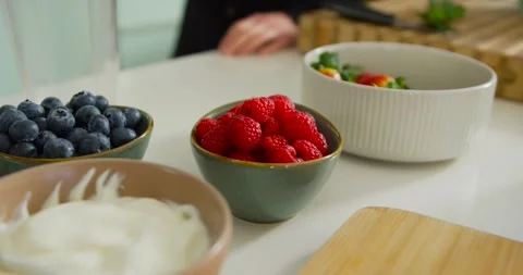 Camera is panning while hands are resting on counter showing raspberries, yogurt Stock Footage 339496906