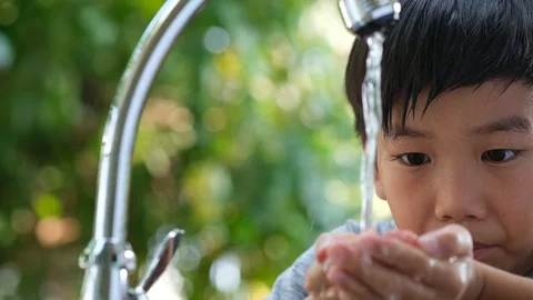 Camera panning , Young Asian boy wash his face by water from faucet in a garden Stock-Footage 126976963