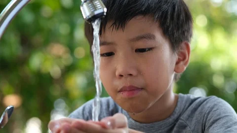 Camera panning , Young Asian boy wash his face by water from faucet in a garden Stock Footage 126977095