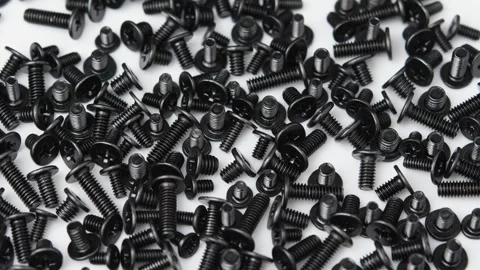Camera pans across assorted black screws for electronics, computer repair and Stock Footage 346875941