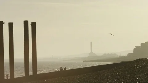 Camera pans across a beach silhouette setting of people and buildings in the dis Stock-Footage 75936489