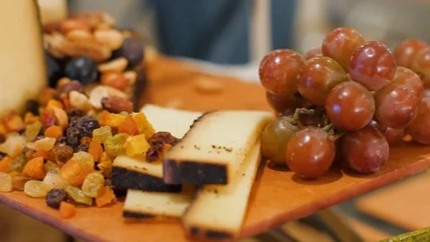Camera pans across a cheese with dried fruit grapes and nuts on a display dis Stock-Footage 107395669