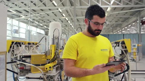 Camera pans across to create a Portrait of factory worker using a tablet Stock Footage 63031311