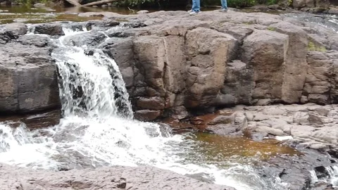 Camera pans across multiple rushing waterfalls surrounded by trees and rocks. Stock Footage 157768137