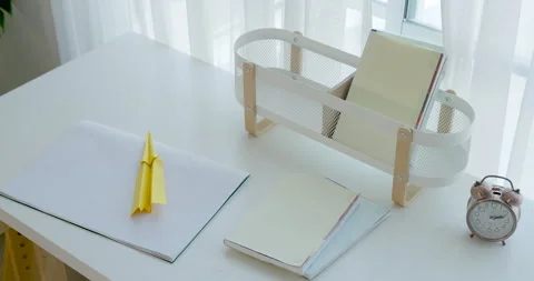 Camera pans across neat white desk with drawing paper, yellow pencil, small Stock Footage 336653278
