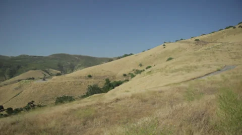 Camera pans across top of rolling hills of grass Stockbeeldmateriaal 31744262