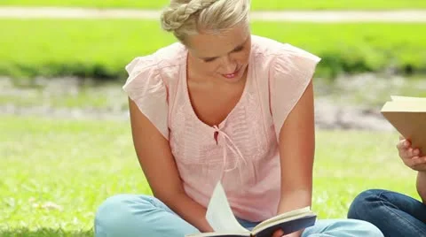The camera pans across two women reading books Stock Footage