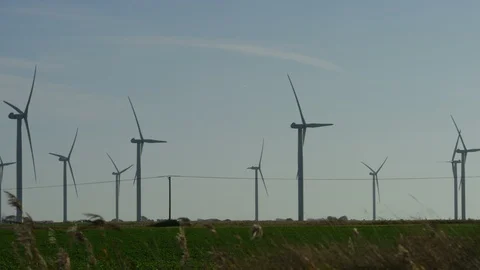 Camera pans across a wind farm to see wind turbines generating power, in slow mo Stock Footage 98017855