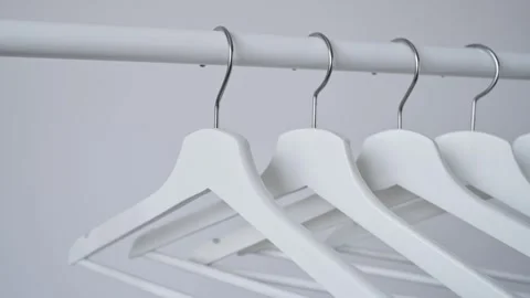 Camera pans along white wooden hangers hanging on wardrobe rod. Empty hangers Video stock 340266725