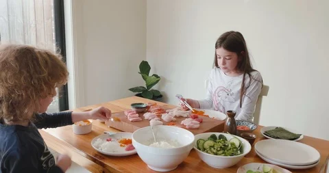 Camera pans around two young children, a boy and a girl,eating sashimi Video stock 115545550
