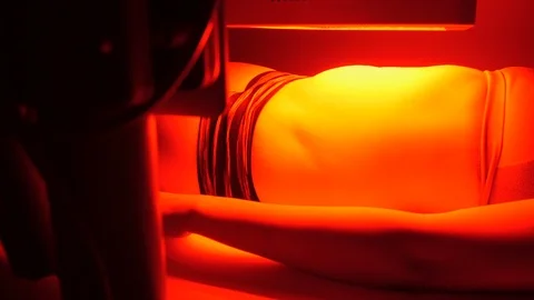 Camera pans clients body up while under infrared lamp Stock Footage 107759800