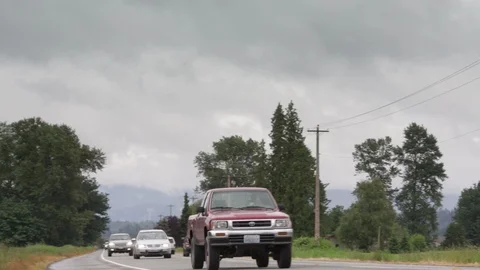 Camera pans moving traffic to red barn with silo under thick white clouds Video stock 86757371