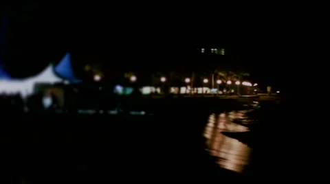 Camera pans from the ocean over to a Hawaii beach concert in progress at night Video stock 42960179