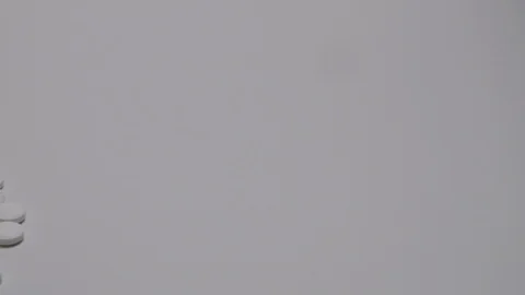 Camera pans over to bottle of pills poured out onto white surface. Stock Footage 108033460