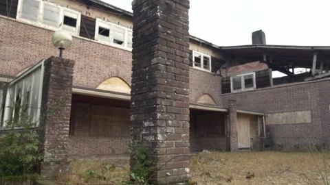 Camera pans over an old abandoned brick building with broken windows Stock Footage 292924534