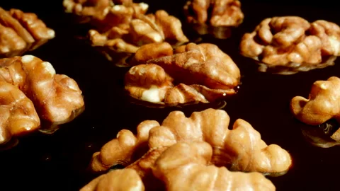 Camera pans over roasted full walnuts wrapped in melted chocolate. Close-up. Видео 149159783