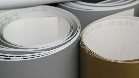 Camera pans over several standing rolls of foil. There are grey and golden foils Stock Footage 163077865